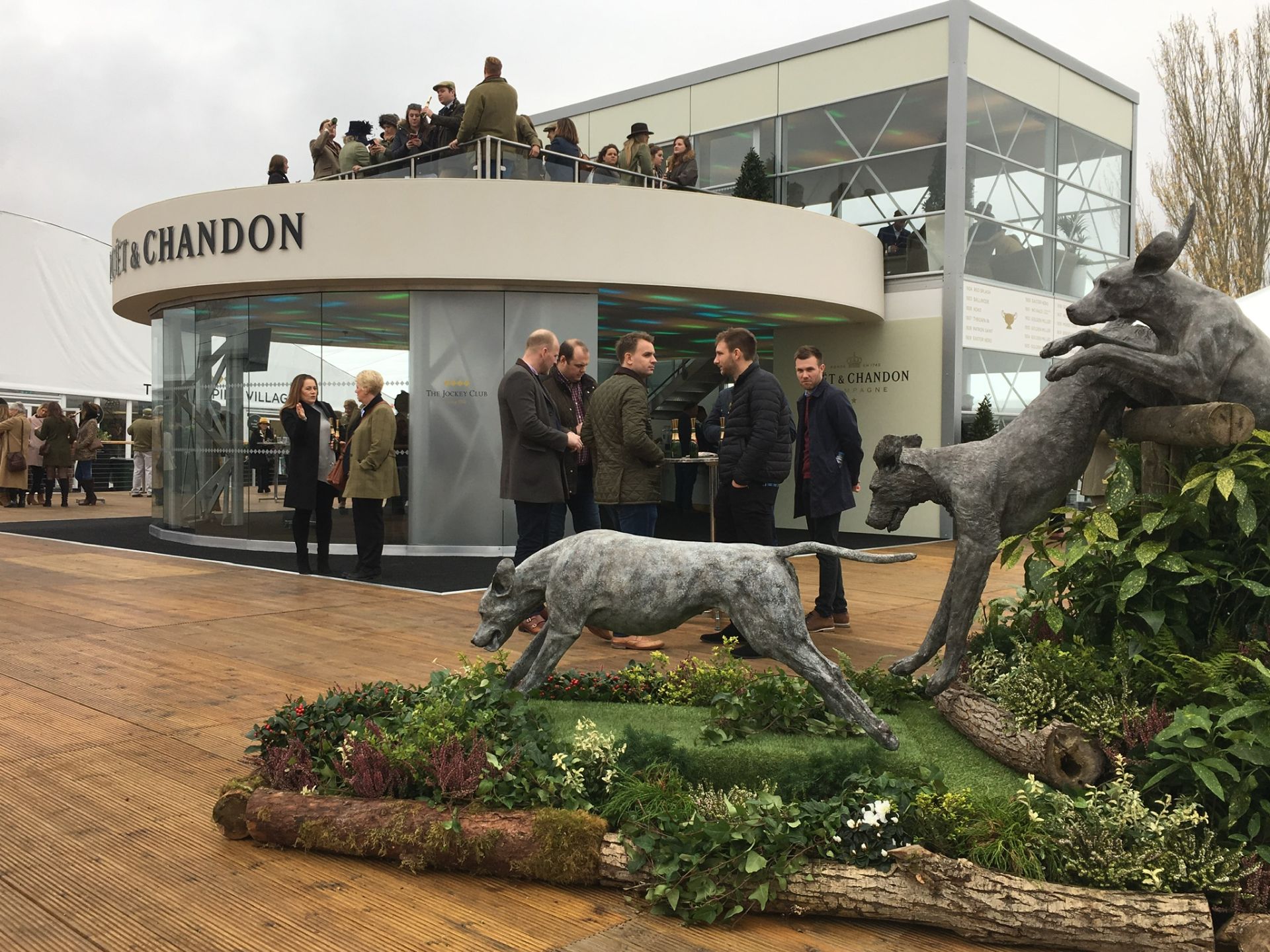 temporary event building moet and chandon with planted feature jumping dog statue infront, surrounded by logs and green planting