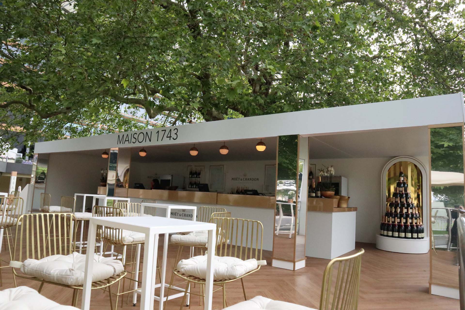 temporary event structure of a bar featuring champagne and gold and white furniture