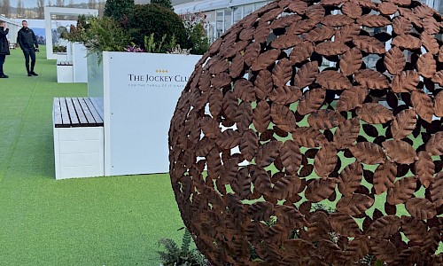 Cheltenham Festival planted statue with bench in background